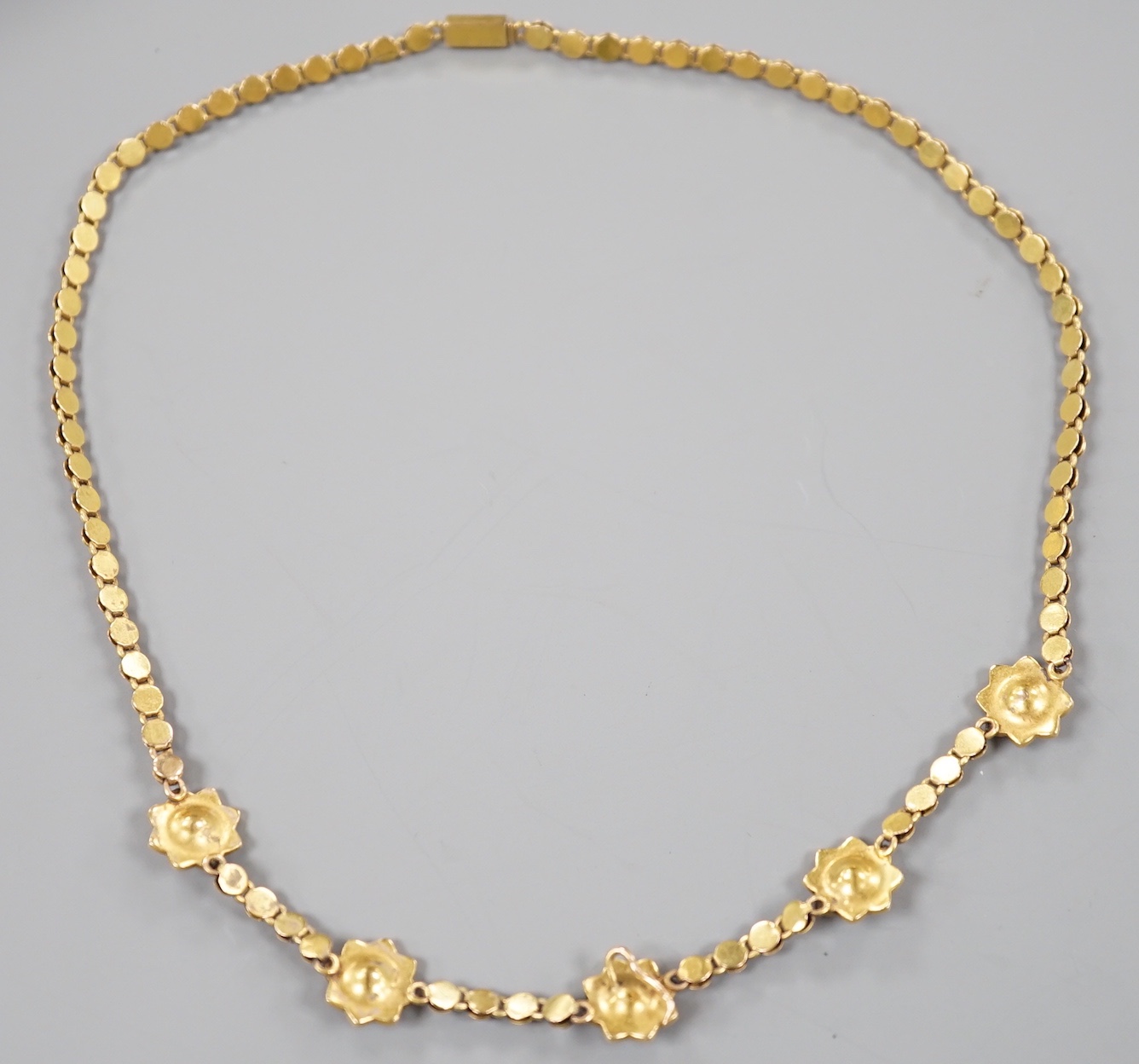 A late Victorian yellow metal and seed pearl set flower head motif necklace, (lacking drop pendant), 36cm, gross weight 18 grams.